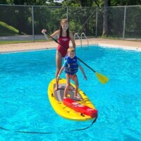 Scout paddle boarding with live guard in pool photo